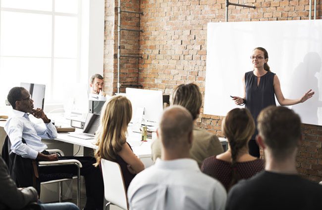 Woman in front of a white board teaching employees about new record retention policies.